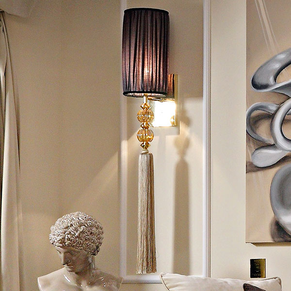 <strong>G1191</strong><br>
applique 1 luce in acciaio finitura gold con sfera in cristallo ambra e pendente fiocco sfilato, completa di paralumi  
25 x 25 x 120 cm