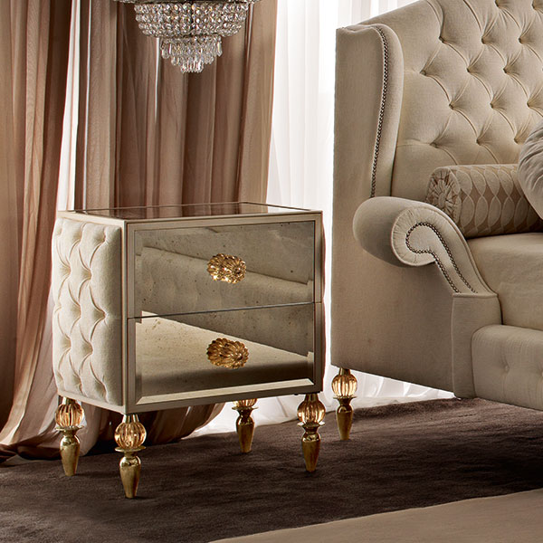 <strong>GL1311</strong><br>
comodino 2 cassetti, fianchi capitonnè, piedini in acciaio finitura gold con sfera in cristallo ambra, completo di pomi ambra  
64 x 45 x 71 cm
